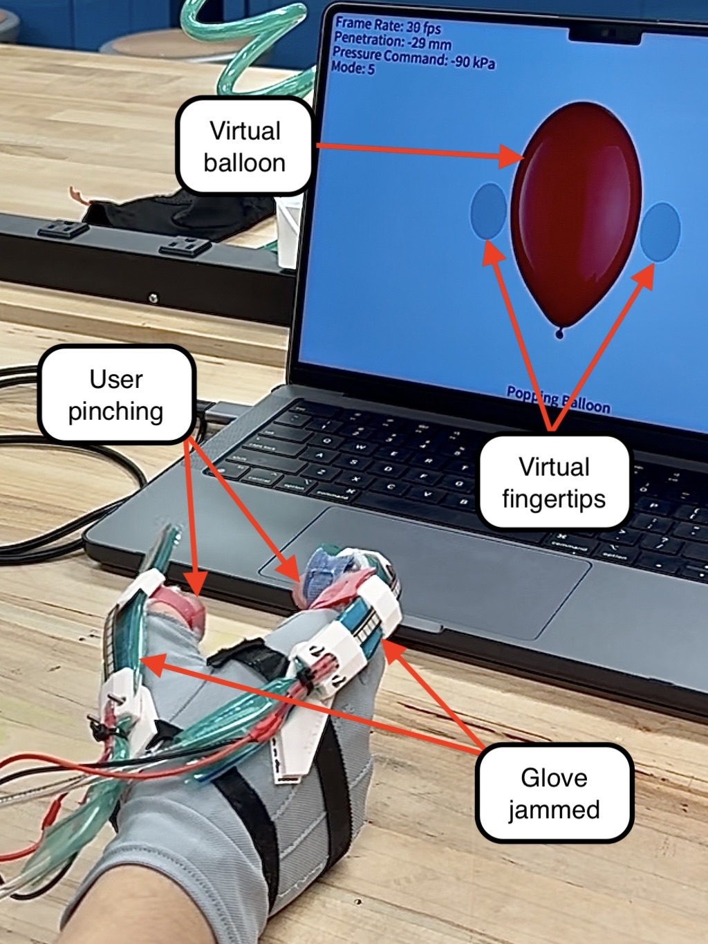 A user pinching in the glove in front of a laptop showing a virtual balloon between two virtual fingertips