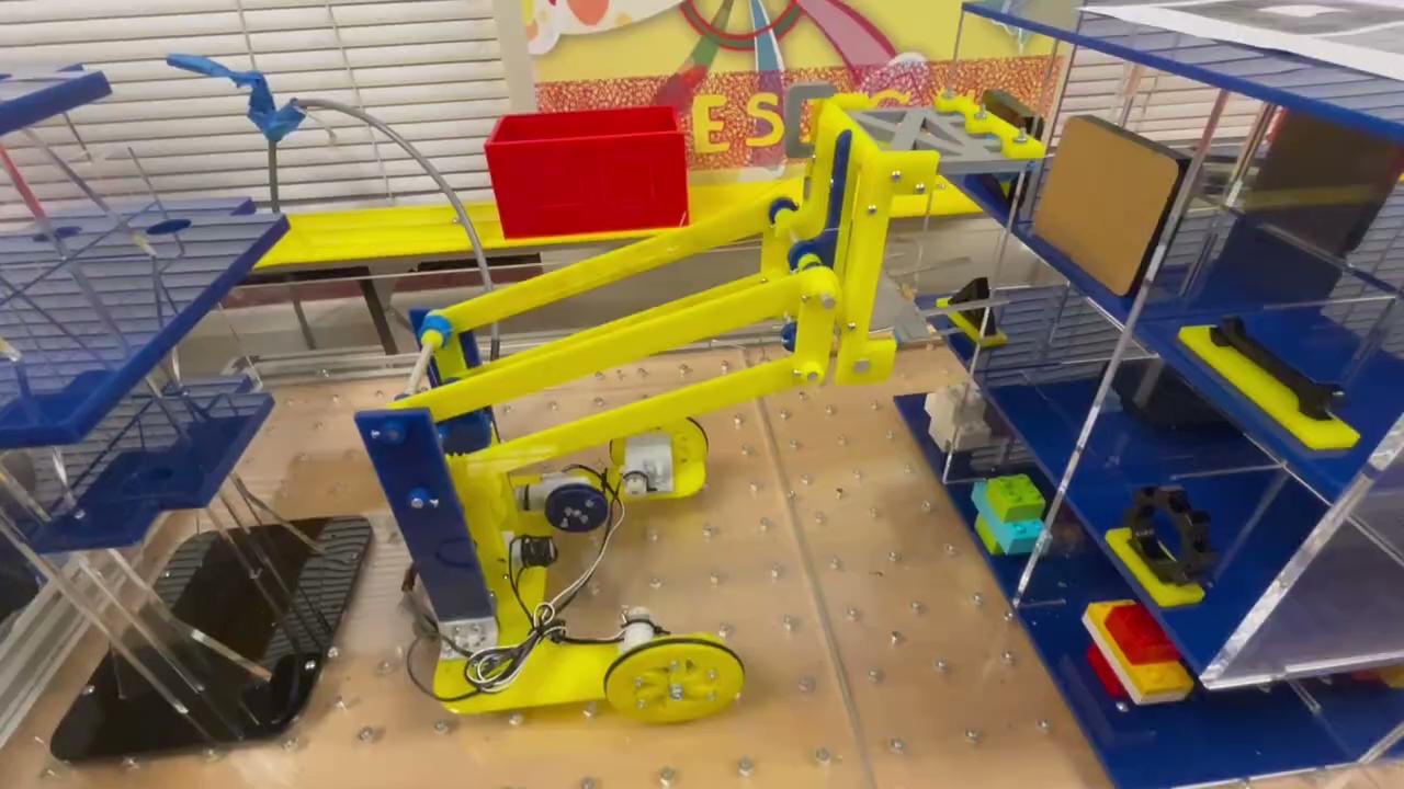 The robot on the contest table with its lift raised toward the upper floors of the model Geisel Library